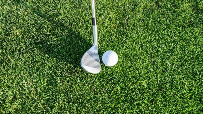 Golf club and ball on green grass, ready for a swing in a close-up view